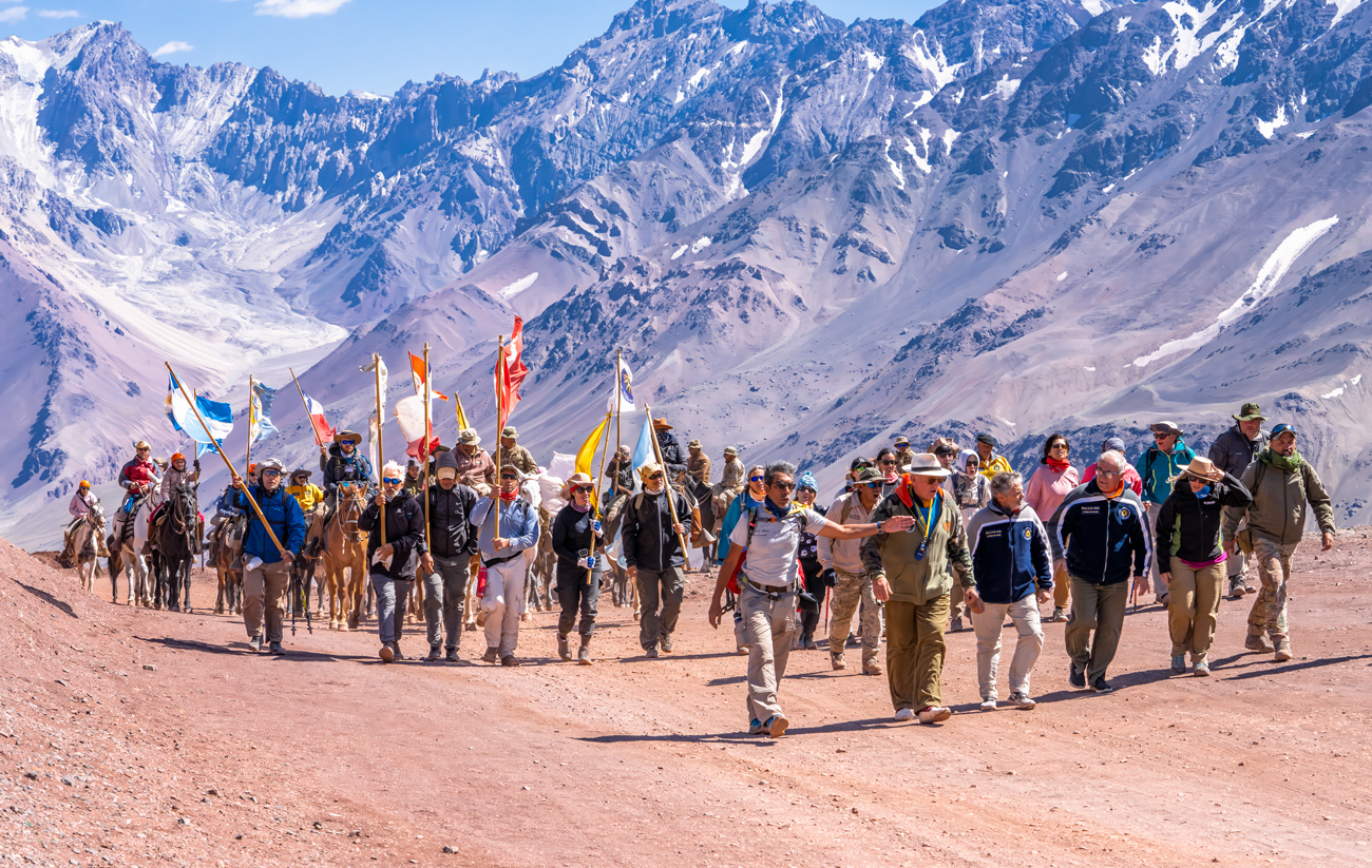 Grupo de expedicionarios caminando en los Andes con banderas